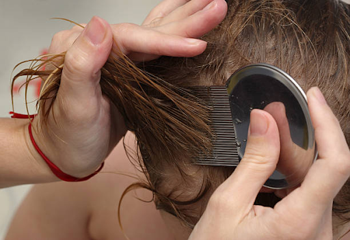 mom combing child's hair looking for head lice symptoms
